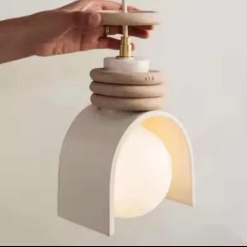 Close up of person adjusting a modern pendant light fixture with a neutral background