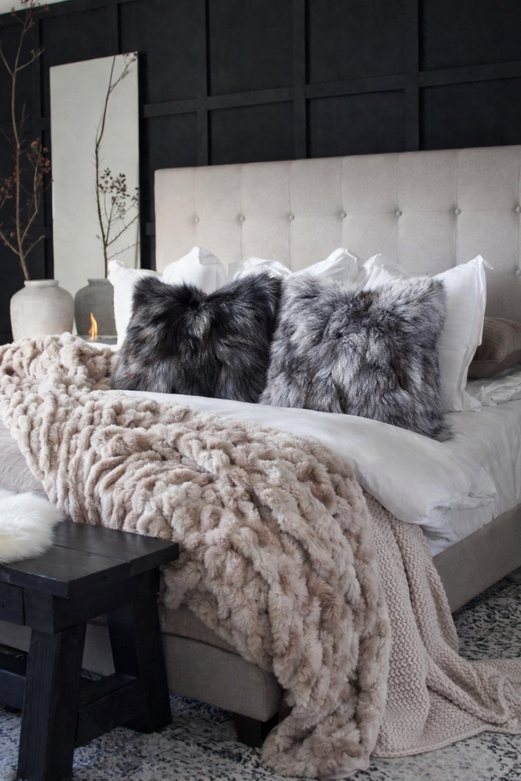Cozy bedroom with bed featuring fluffy Real Fox Fur Pillows in Silver Fox Fur tones against a dark paneled wall
