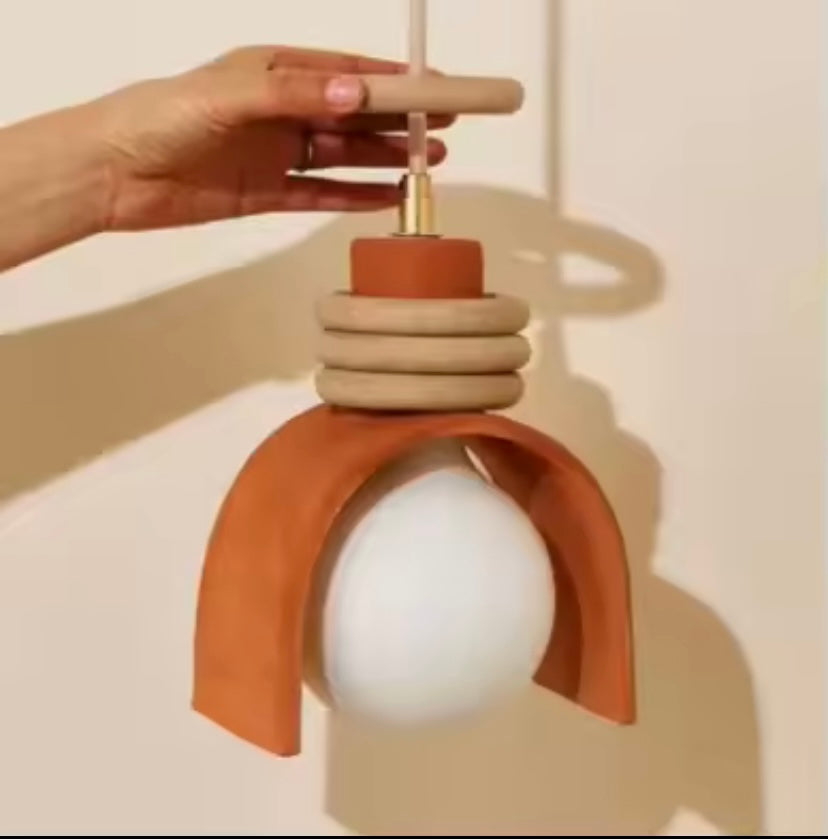 Hand adjusting a terracotta coloured pendant light fixture