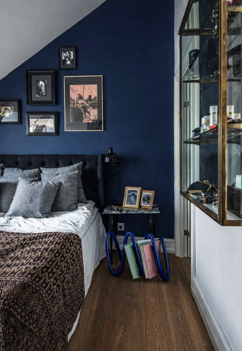 Modern bedroom with navy accents and Ripple Rack in blue with books in it on the bedroom floor